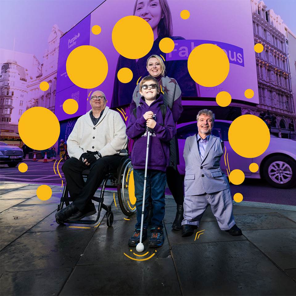 An image of a Young, blind boy, a man in a wheelchair, and a woman behind him alongside Mike Adams at the Piccadilly lights on Purple Tuesday. A wave of purple and some yellow circles are eminating out from behind them representing 