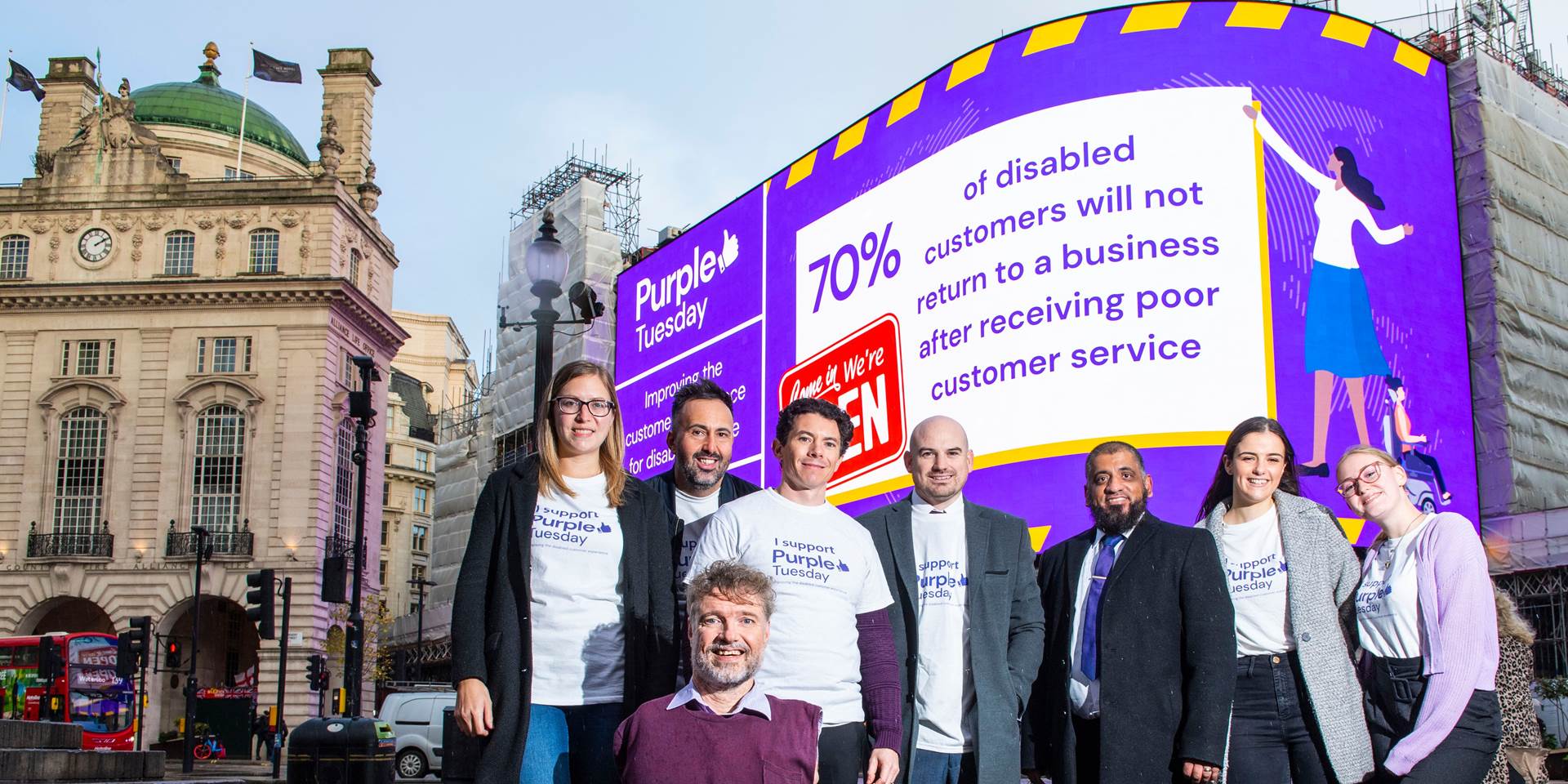 A picture of the Purple Tuesday team in-front of a Purple Tuesday sign in Piccadilly Square
