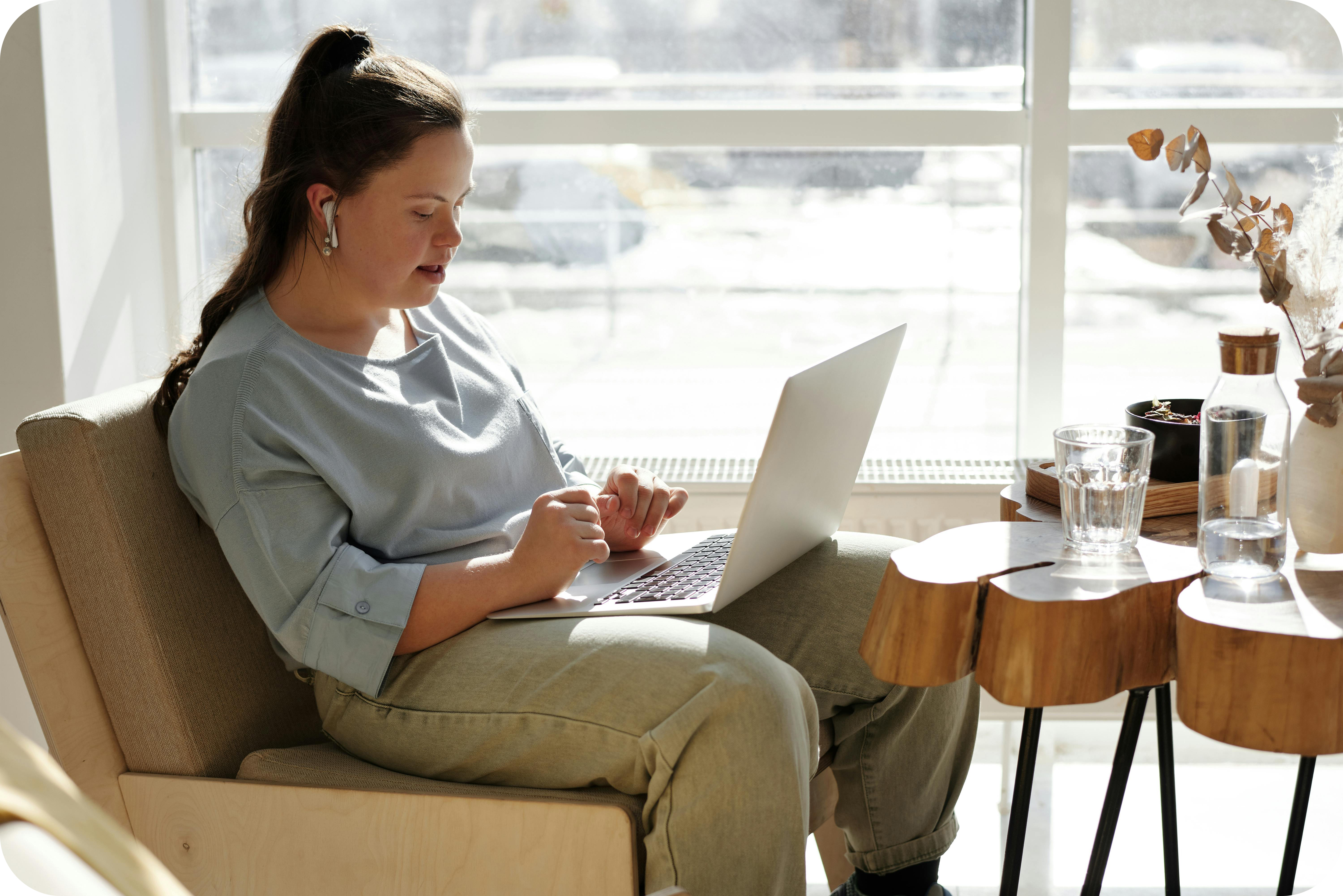 A women with Down Syndrome sitting and working on a laptop